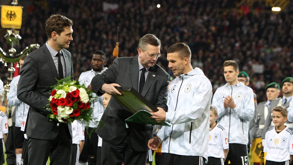 DFB-Präsident Reinhard Grindel überreicht Podolski zum Abschied ein Bild. Generalsekretär Dr. Friedrich Curtius (l.) hält den Blumenstrauß