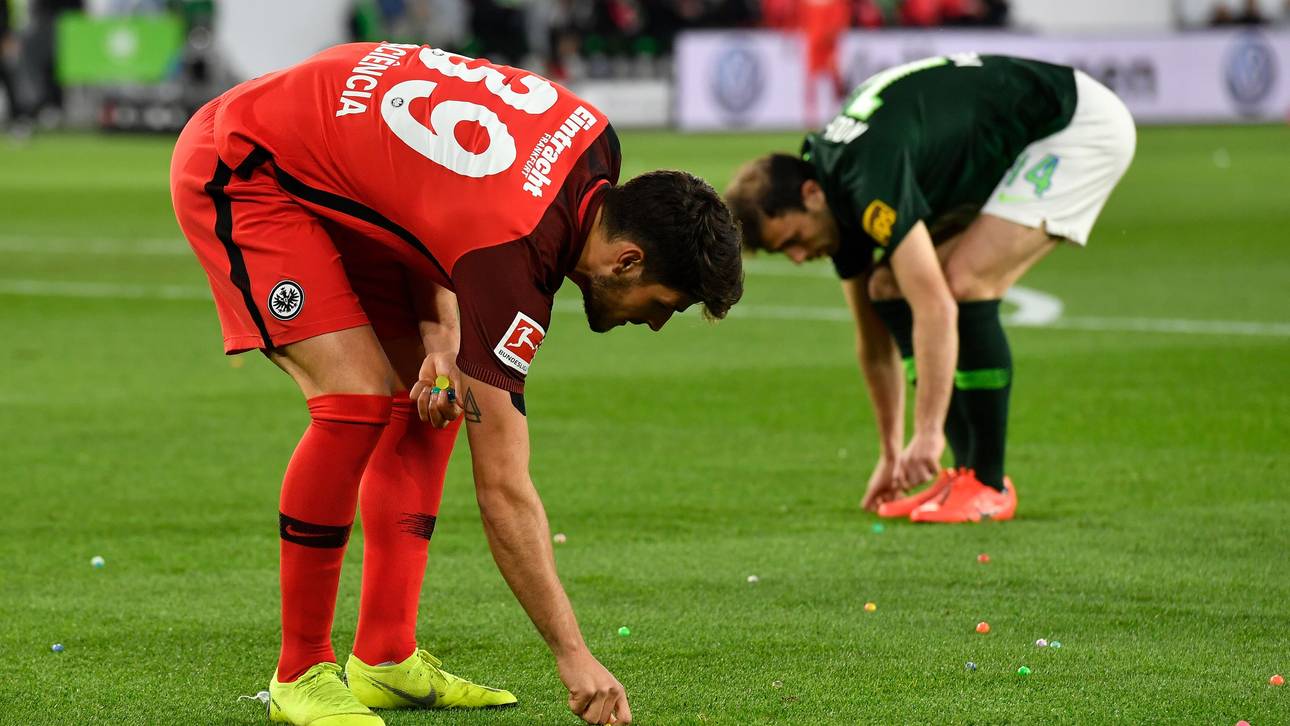 Frankfurts Goncalo Pacienca (l.) und Wolfsburg Admir Mehmedi packen mit an und sammeln die von den Rängen auf den Rasen geworfenen Ostereier