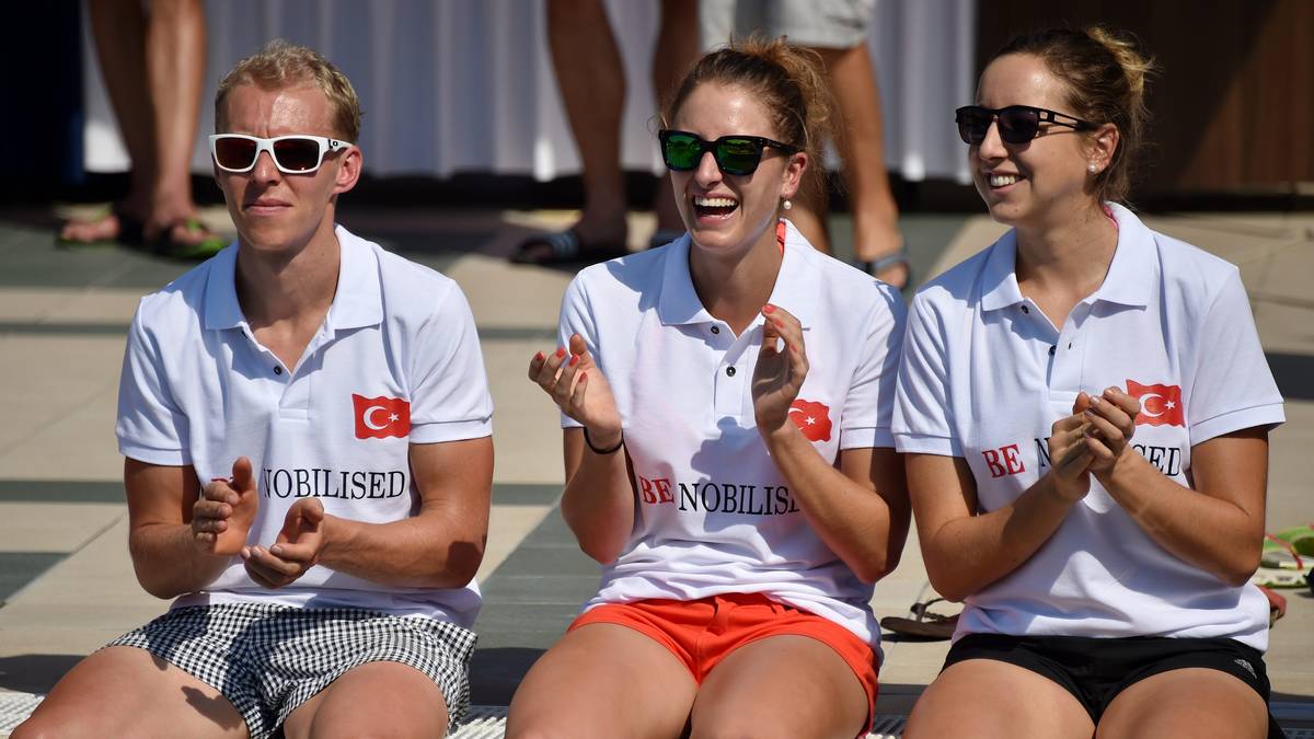 Die Biathleten Daniel Böhm, Vanessa Hinz (m.) und Franziska Preuß schauen der Show vom Beckenrand staunend zu und genießen die warmen Sonnenstunden fernab vom harten Trainingsalltag. Vergangene Saison hat sich dieser gelohnt: Alle drei holten WM-Gold - Böhm in der Männer-, Hinz und Preuß in der Frauen-Staffel