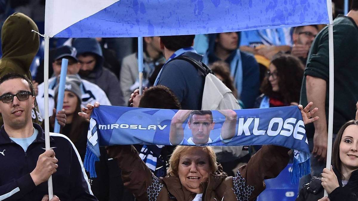 Klose ist zwar Deutscher, aber nach seiner Zeit in Rom heißt seine Heimat auch Lazio. Auf dem Plakat ist Kloses Trikot mit der Nummer elf zu sehen. Im Hintergrund sind die Farben der deutschen Fahne und die Vereinsfarben von Lazio abgebildet