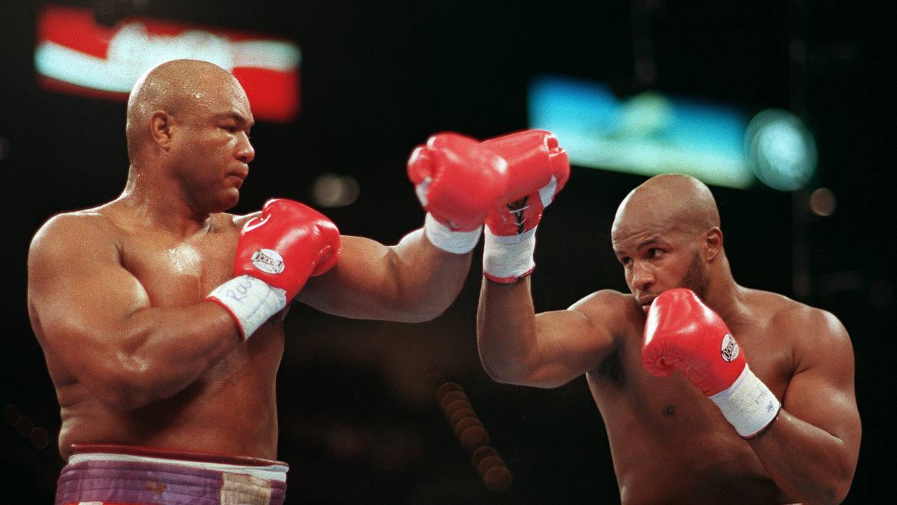 George Foreman (L) throws a right jab to