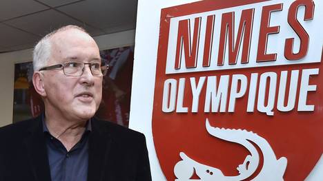 Christian Perdrier neben dem Logo des französischen Zweitligisten Olympique Nimes 