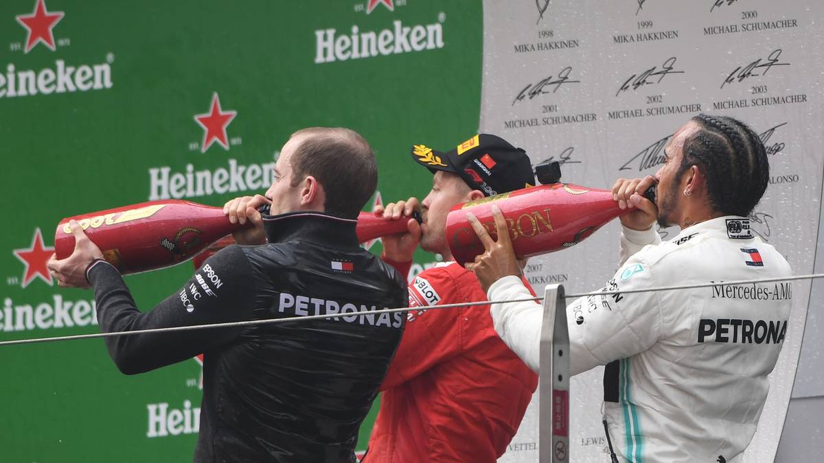 Zum Abschluss der Feierlichkeiten genehmigen sich Hamilton, Vettel und ein Teammitglied von Mercedes einen großen Schluck