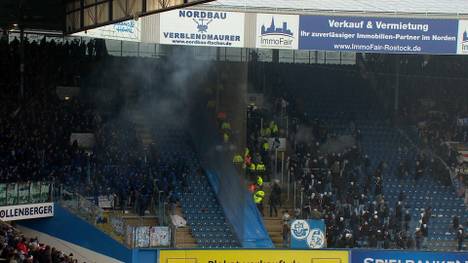 Das Spiel zwischen Rostock und Schalke ist aufgrund von Ausschreitungen auf der Tribüne für eine halbe Stunde unterbrochen. Kurios: Vor dem Wiederanpfiff sieht ein Rostocker noch die Rote Karte.